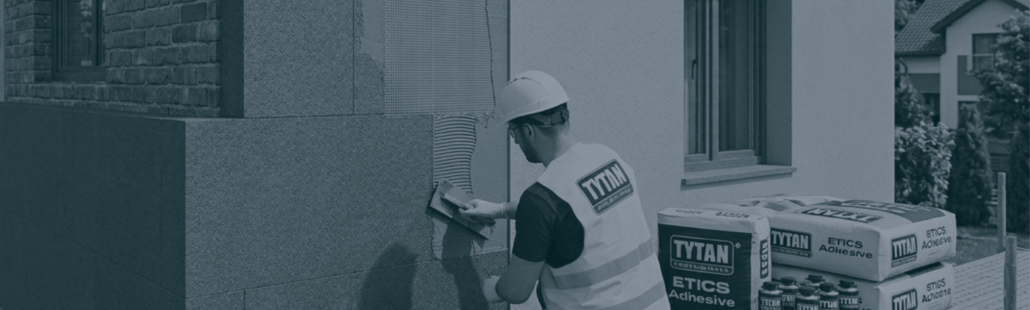 Montaż systemu ociepleń ETICS Tytan Professional z grafitowym styropianem Robotnik budowlany montuje grafitowy styropian na ścianie zewnętrznej z użyciem systemowych produktów Tytan Professional.